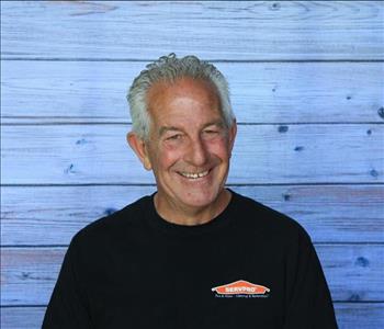 Male employee smiling in front of wooden wall background