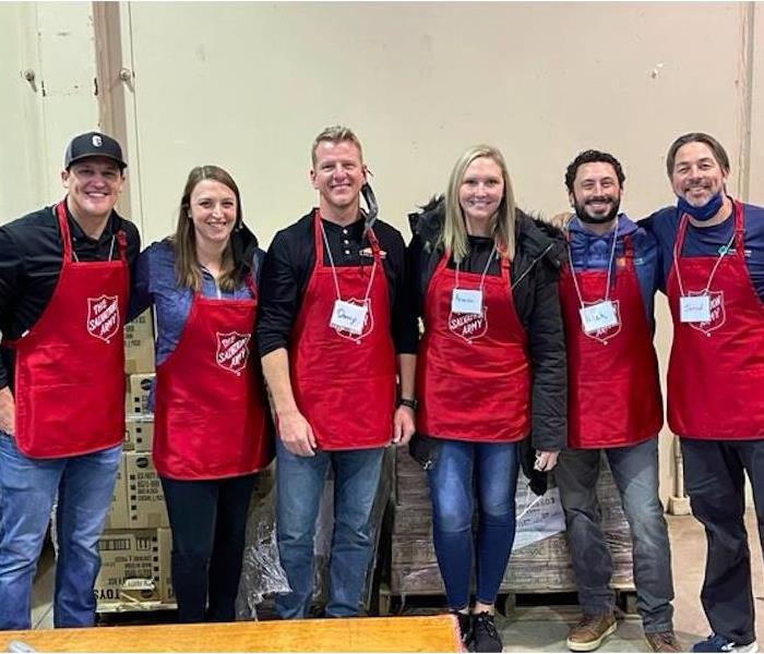 group of males and females standing together with red salvation army aprons