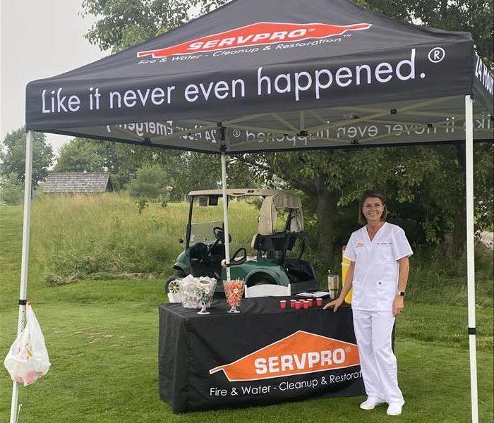 female in scrubs standing in front of table under golf tent