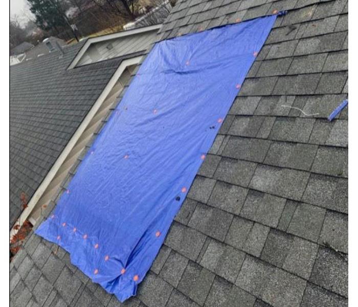 blue tarp covering part of black roof